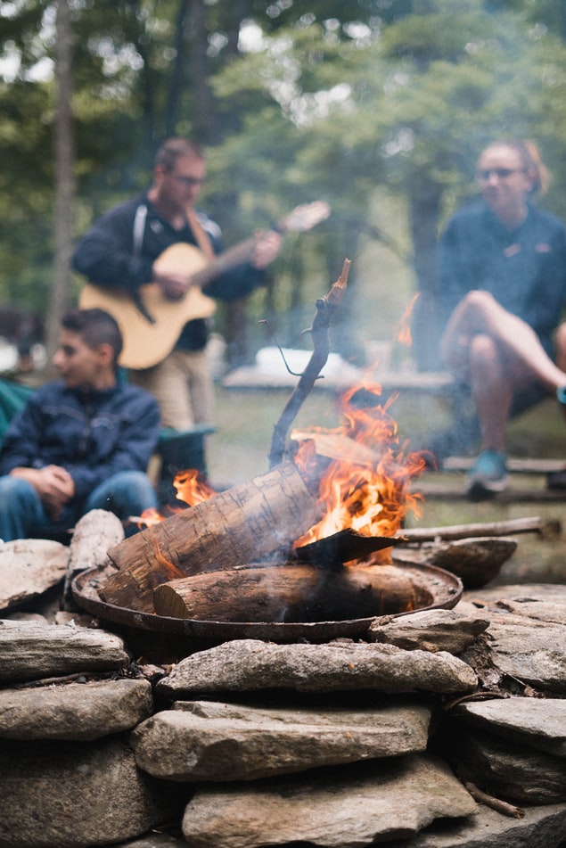 Picture of a people playing the guitar around a campfire.