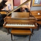 brown grand piano with bench on display in showroom